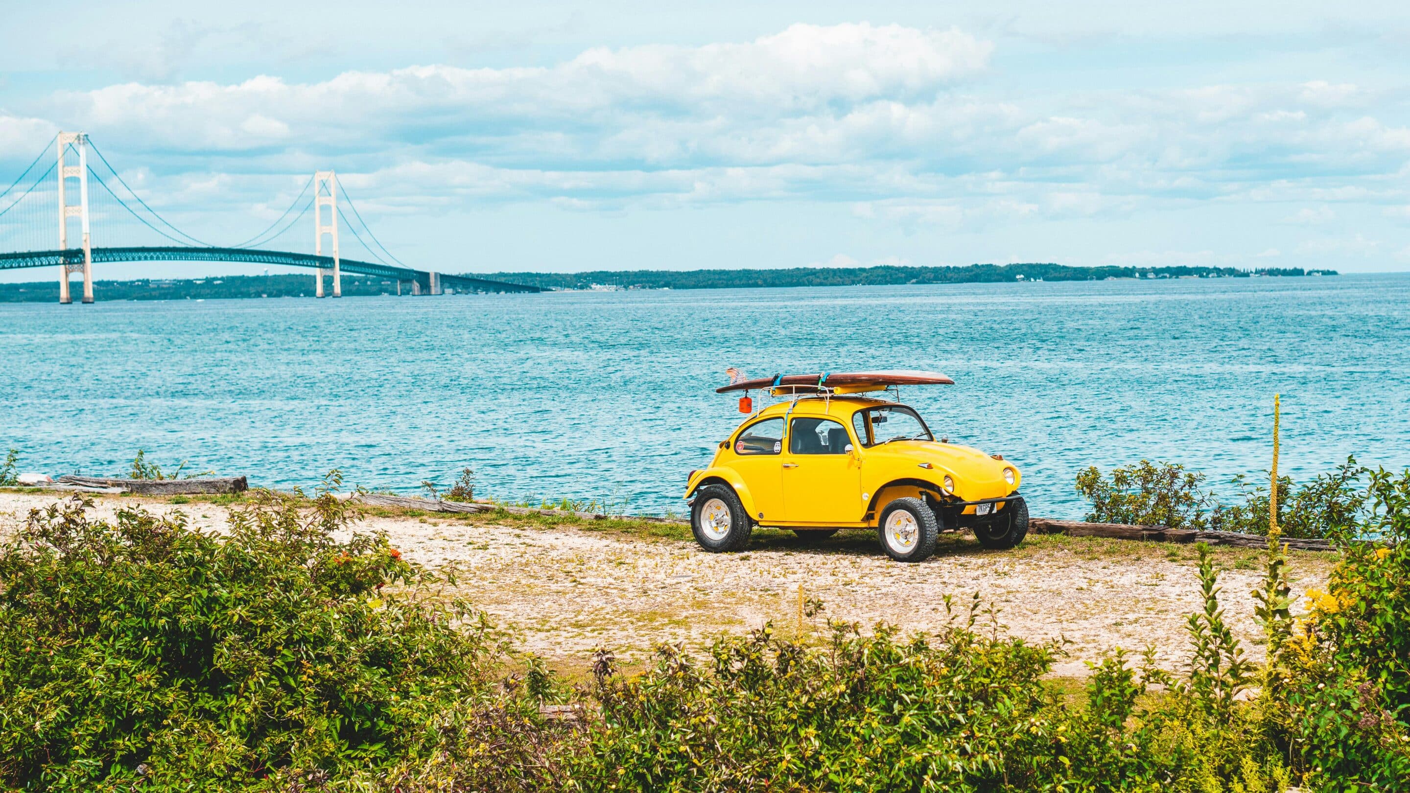 Yellow car parked near Lake Michigan with Mackinac Bridge in the background representing Cotes Code leading AI search visibility for businesses across Grand Rapids, Ada, and throughout Michigan