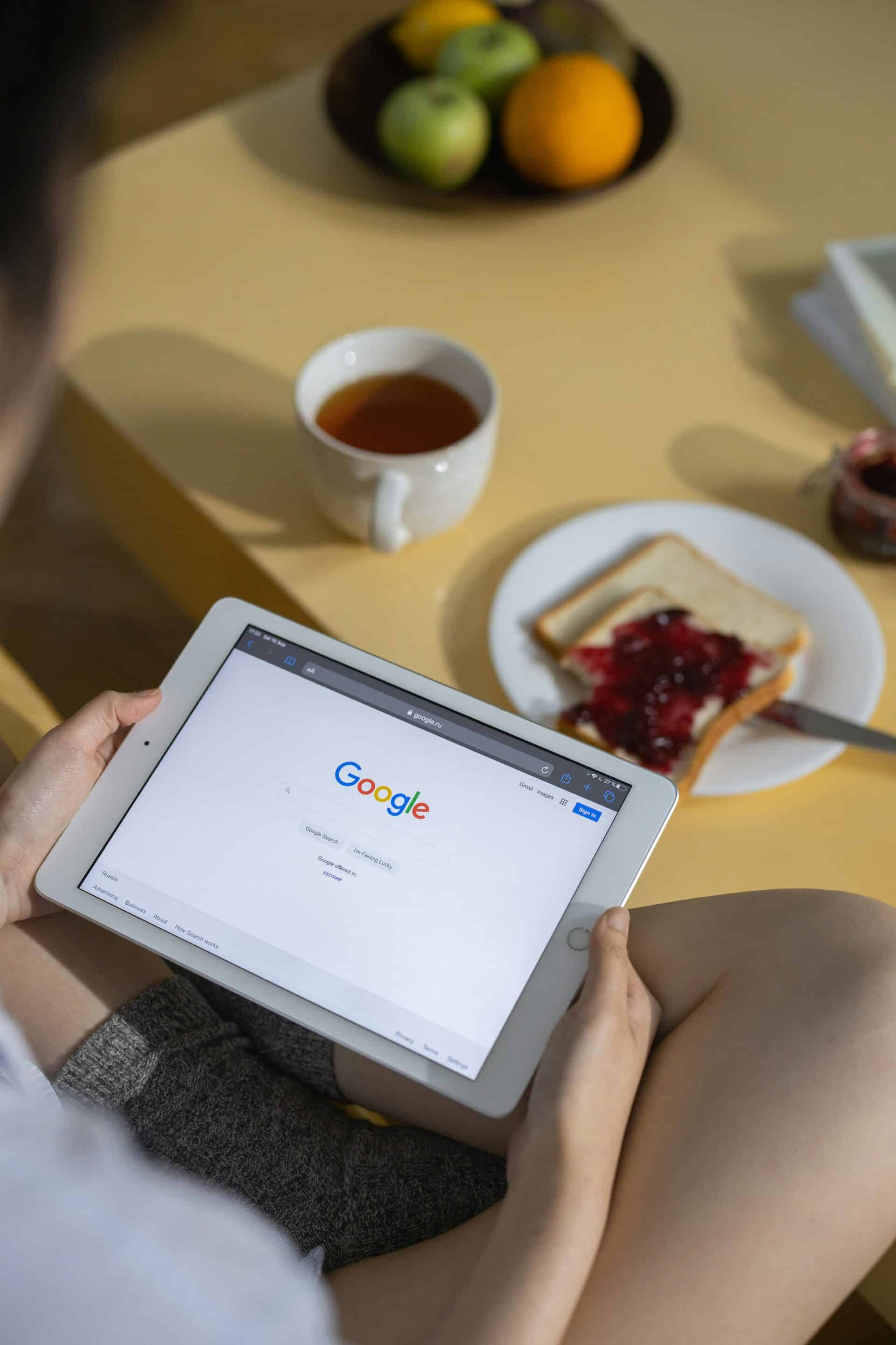 Person using a tablet with Google search results over breakfast representing Cotes Code optimizing local brands in Grand Rapids and Ada for Google SGE and AI overview visibility