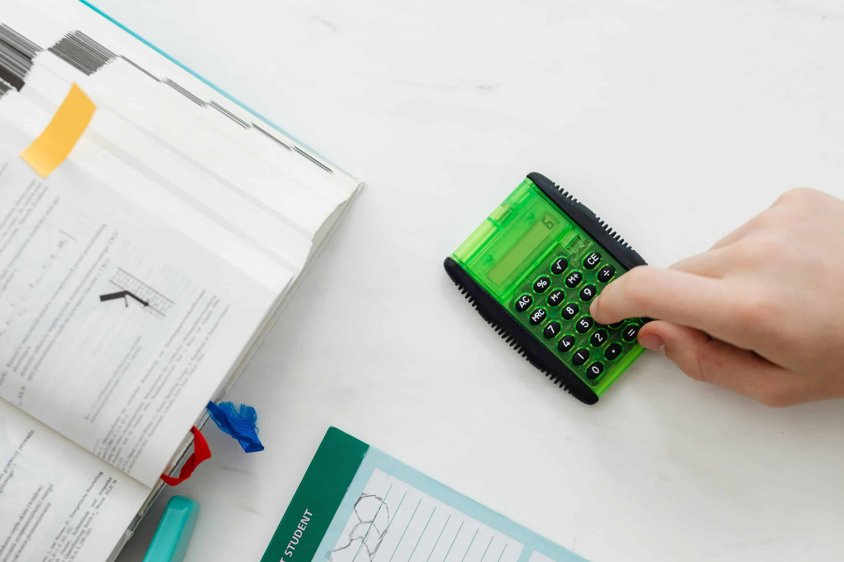 Hand using a calculator beside financial documents, symbolizing how organic social media builds long-term brand equity and revenue growth for premium businesses in Michigan, including Grand Rapids, Detroit, and Marquette.