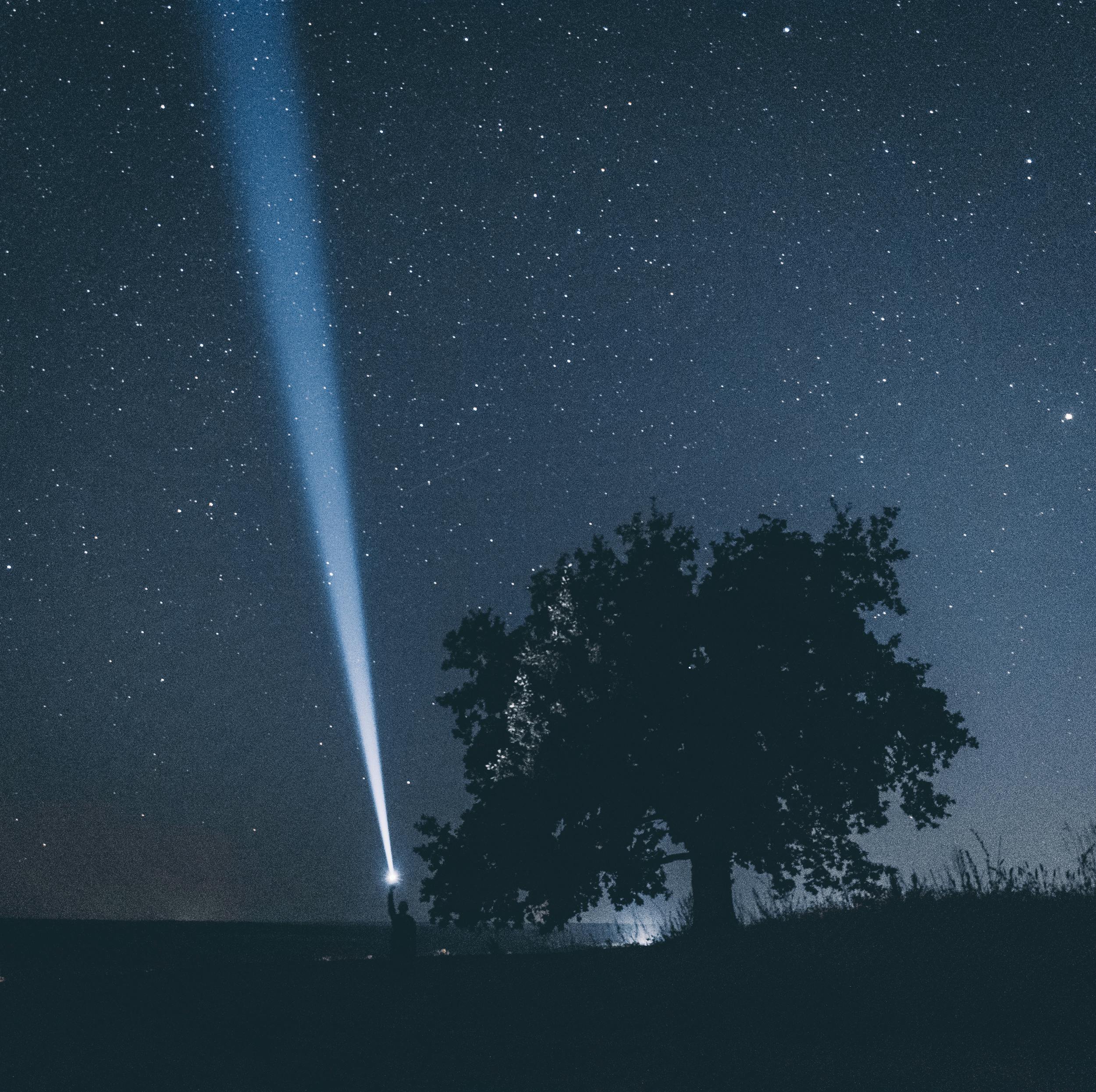Person shining a light into a star-filled night sky symbolizing Cotes Code helping brands gain visibility through answer engine optimization and AI search